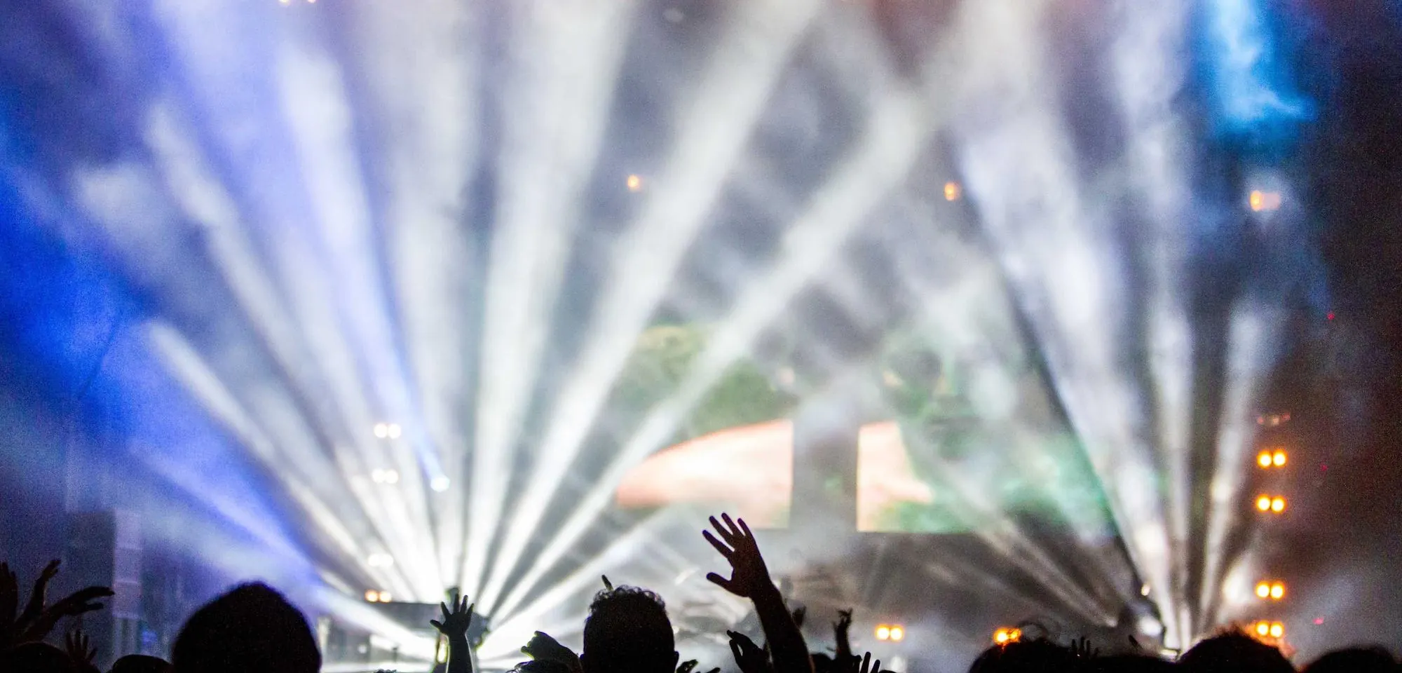 Stage lights sweeping over a crowd at a night show