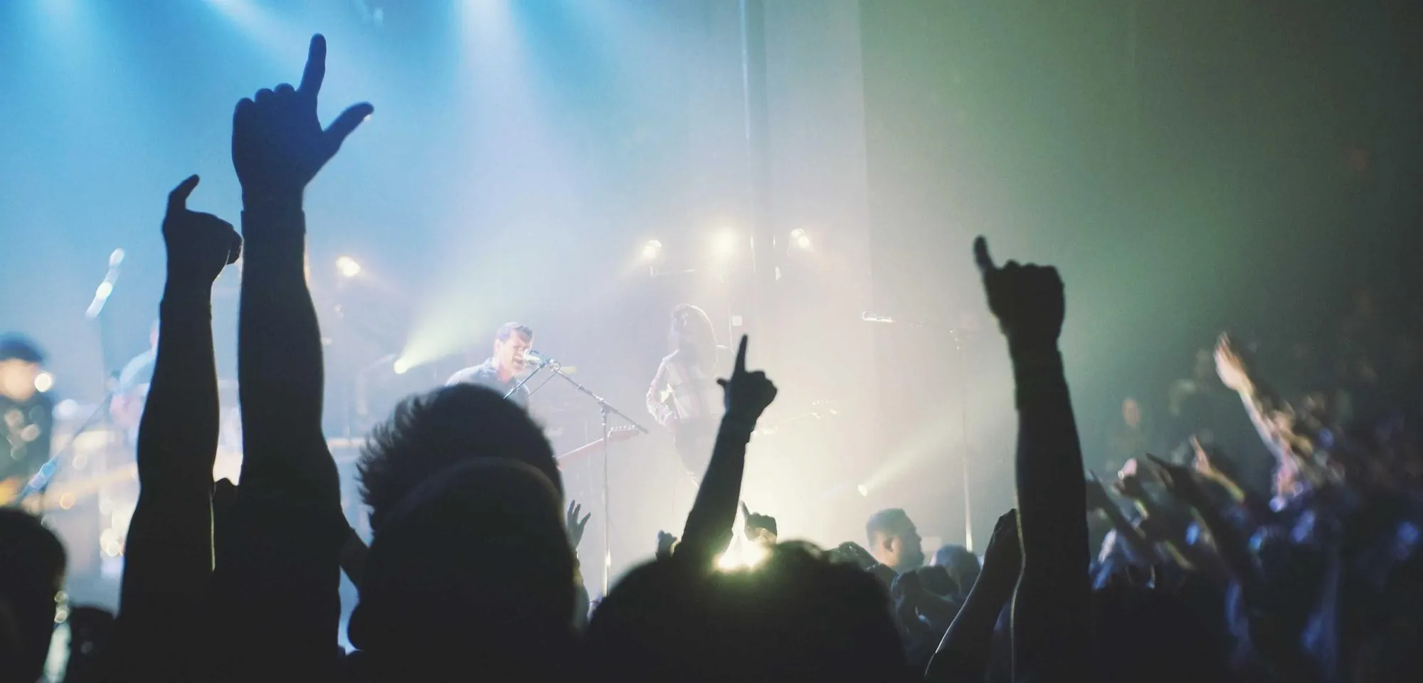 Hands raised under blue concert lights